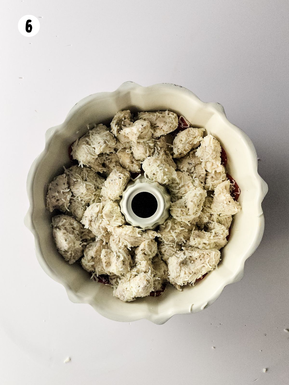 cut up refrigerated biscuits in bundt pan with cheese and spices.