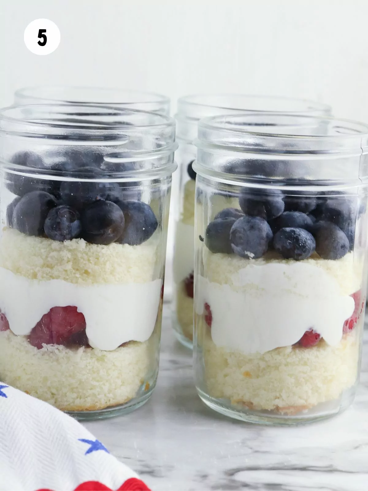glass jars with pound cake, berries and whipped cream.