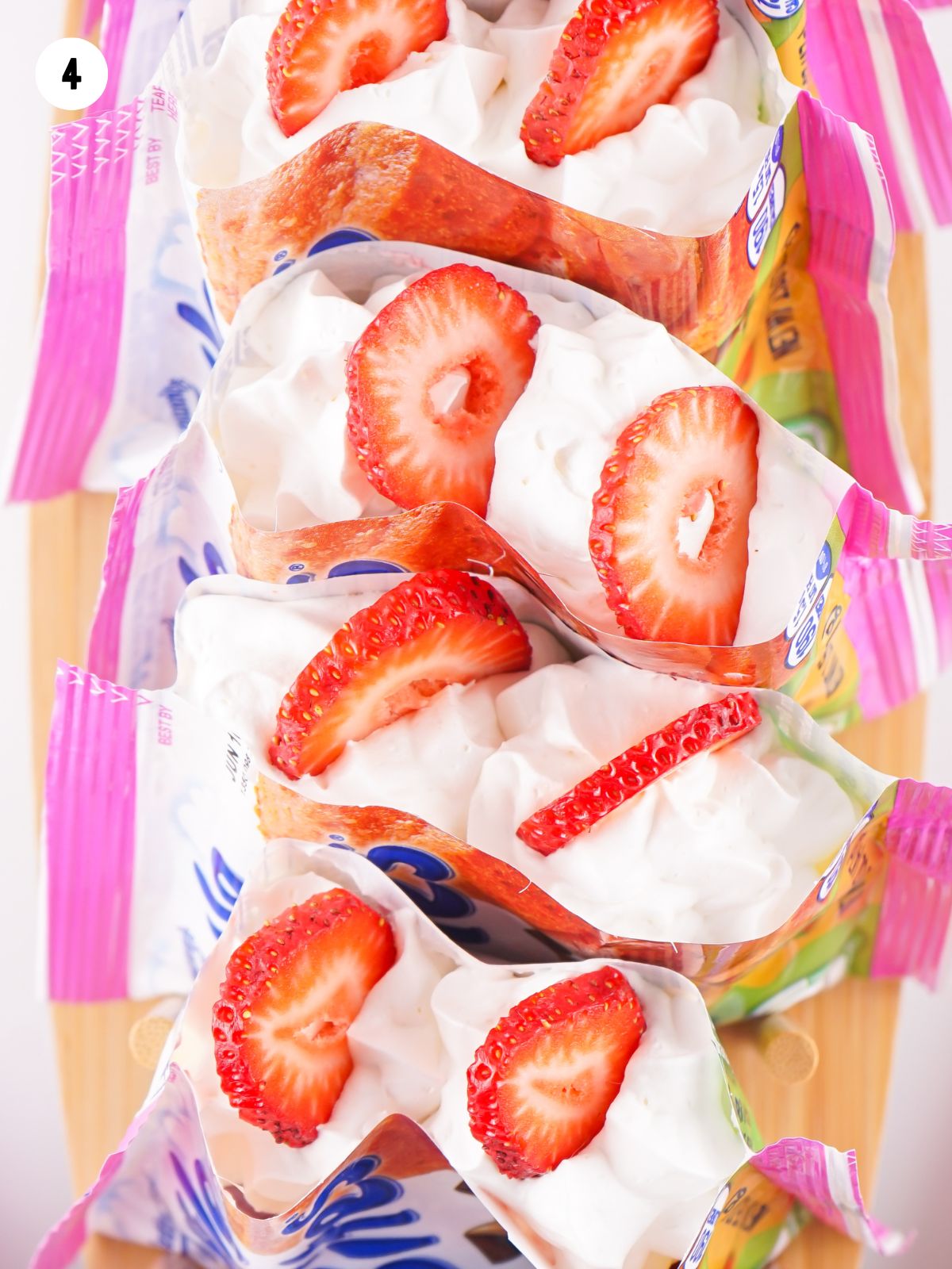 top the bag of mini muffins with whipped cream and sliced strawberries.