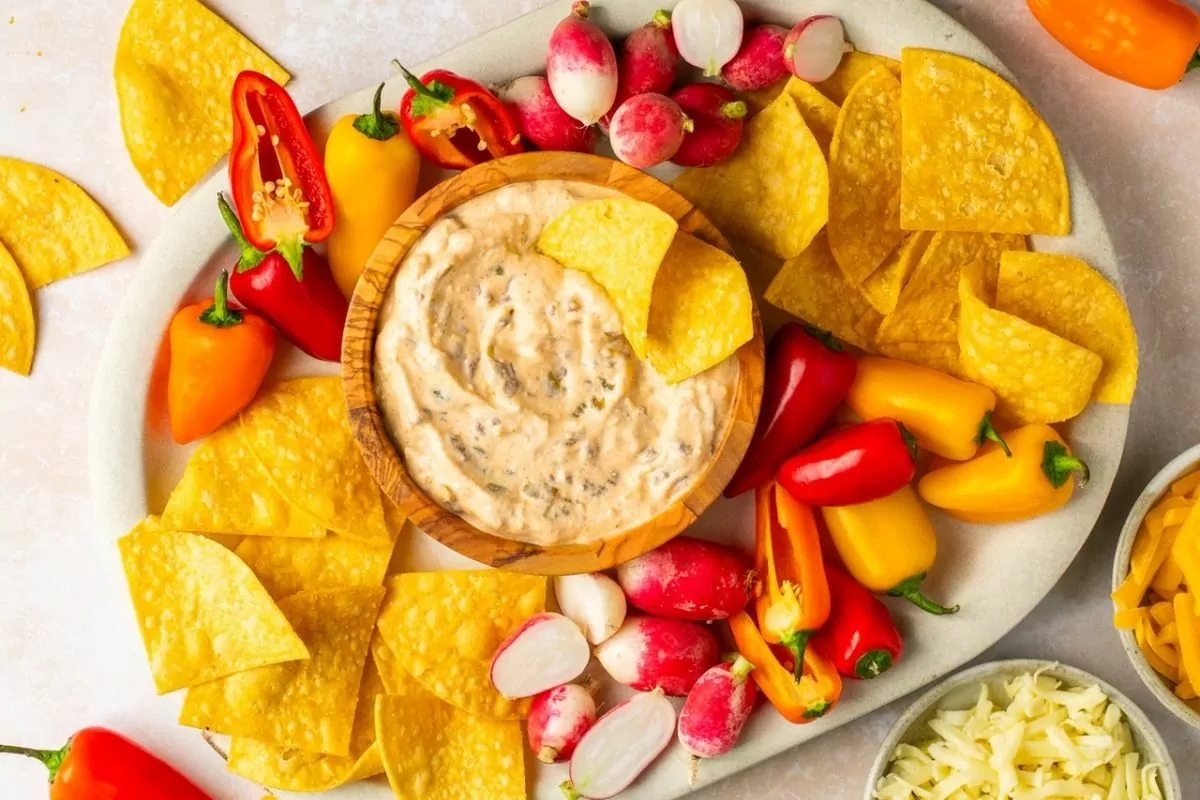 a bowl of cottage cheese queso surrounded by peppers and radishes.