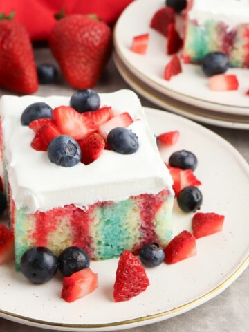 close up of cake on plate with red and blue Jell-O pokes.