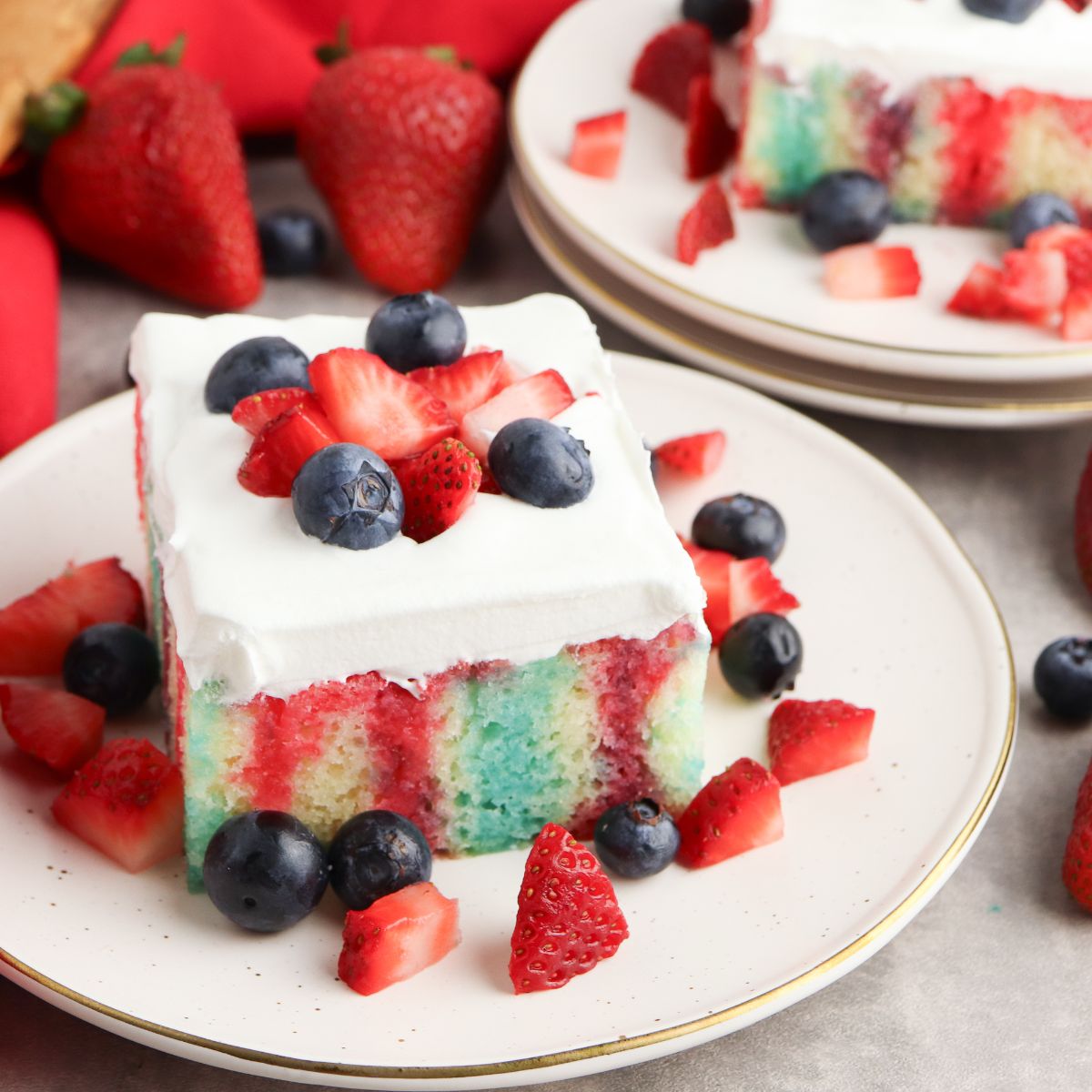 close up of cake on plate with red and blue Jell-O pokes.