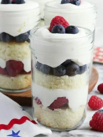 3 glass jars filled with a pound cake, whipped cream and berry dessert.