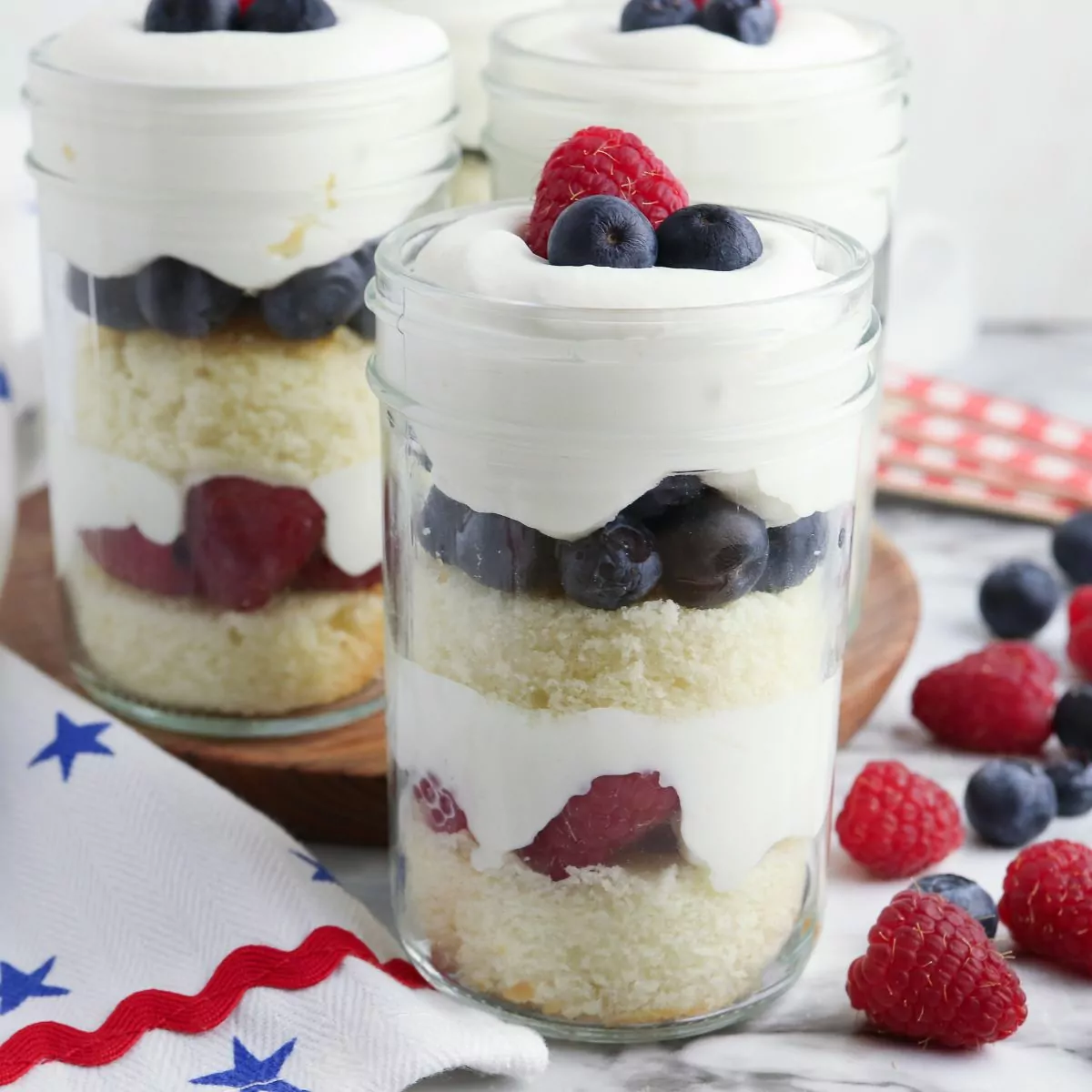 3 glass jars filled with a pound cake, whipped cream and berry dessert.