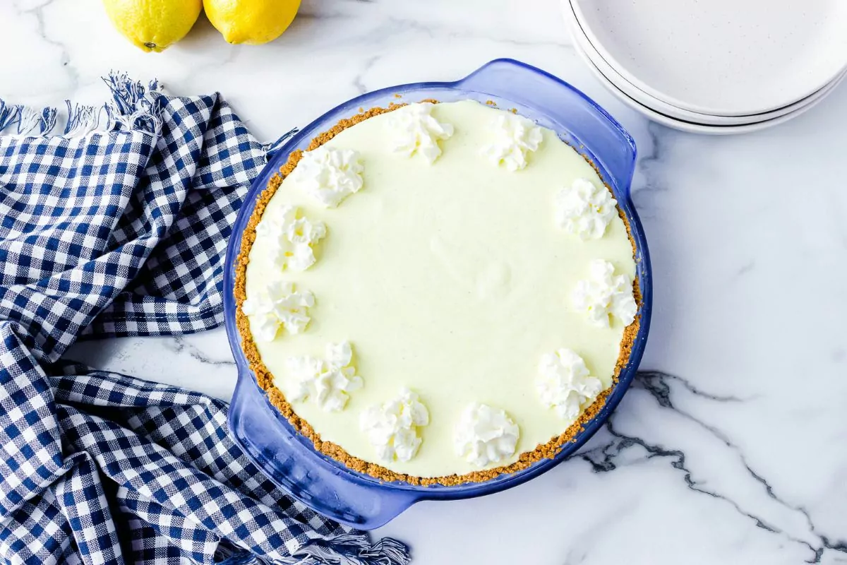 overhead view of frozen lemonade pie in pie dish with blue checked dish cloth.