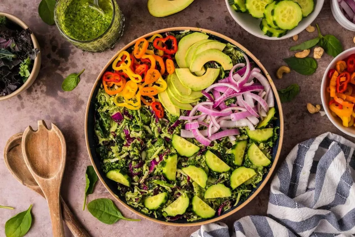 a bowl of green salad with onions, peppers, avocado and onions.