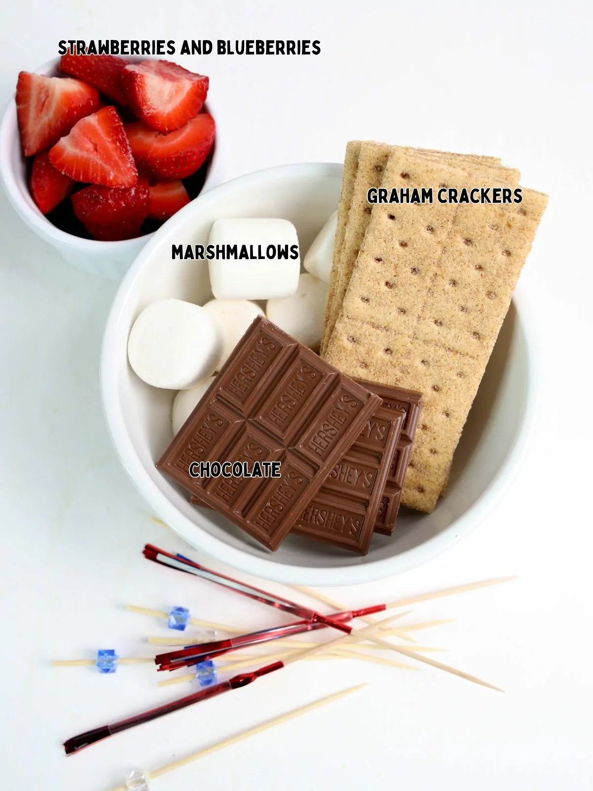 ingredients of candy bars, marshmallows, graham crackers and strawberries, blueberries.