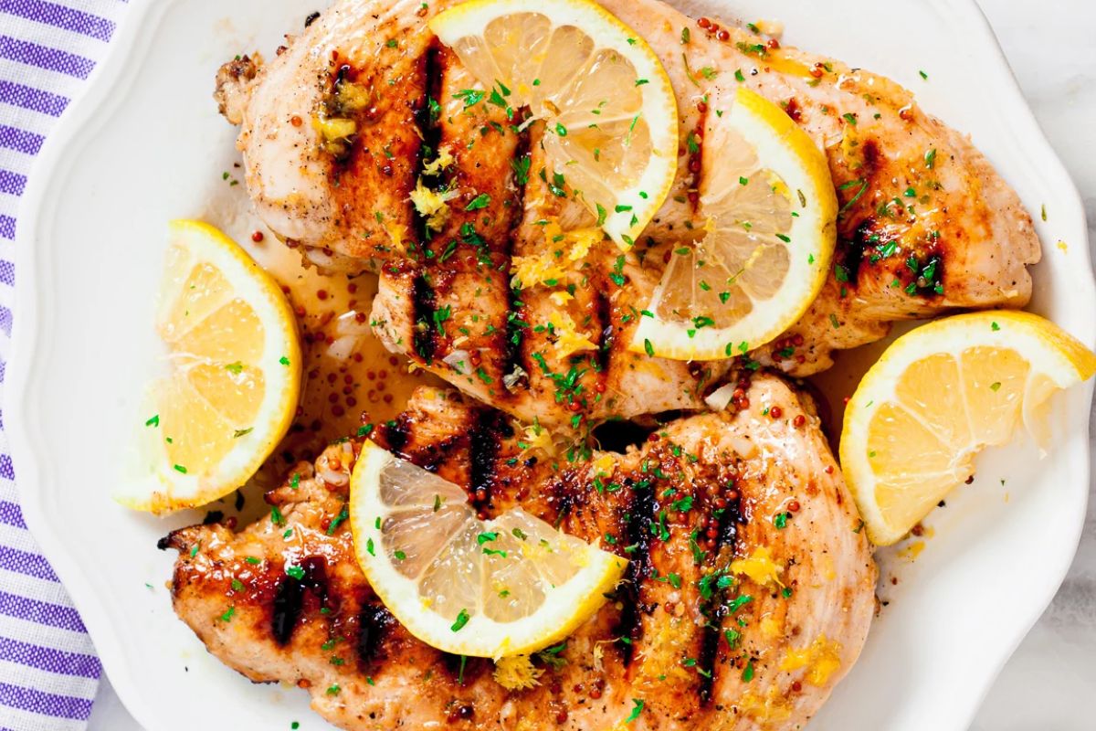 lemon chicken on plate with lemon wedges.