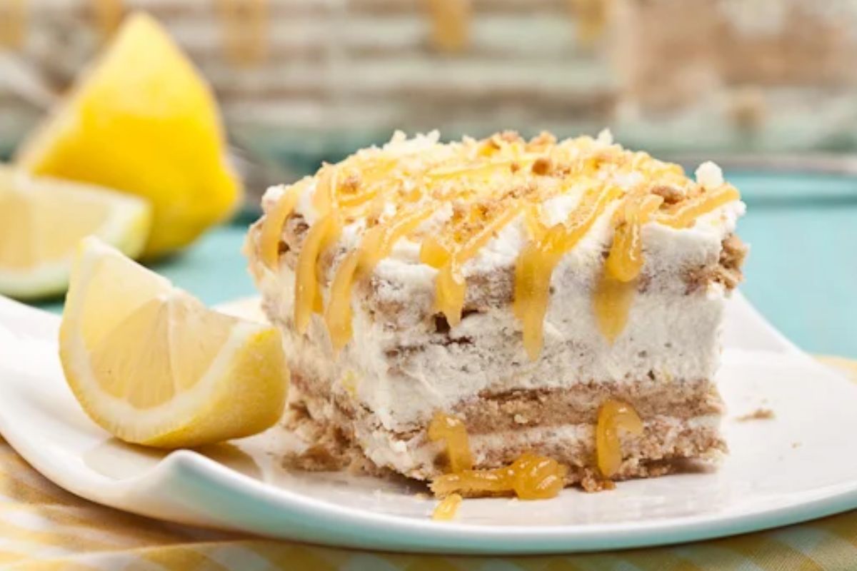 a lemon icebox cake square on a plate with a wedge of lemon.