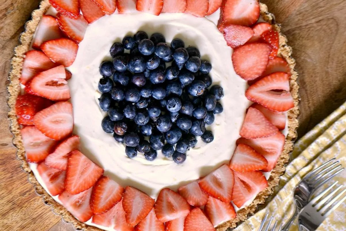 overhead view of a cheesecake pie with strawberries and blueberries.