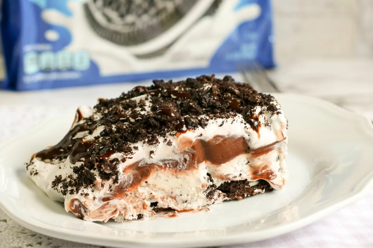 a slice of Oreo Pudding Dessert on white plate with package of cookies in background.