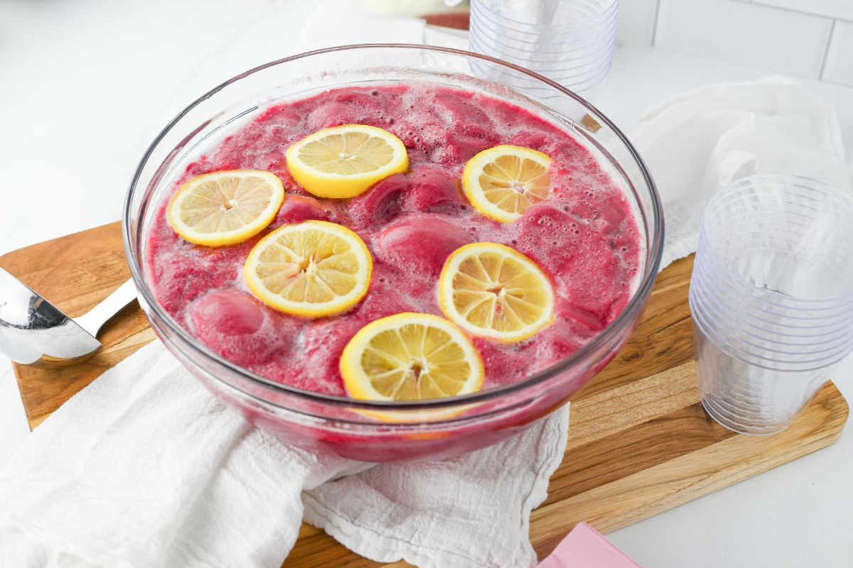 Clear bowl filled with pink punch with lemon slices on top.