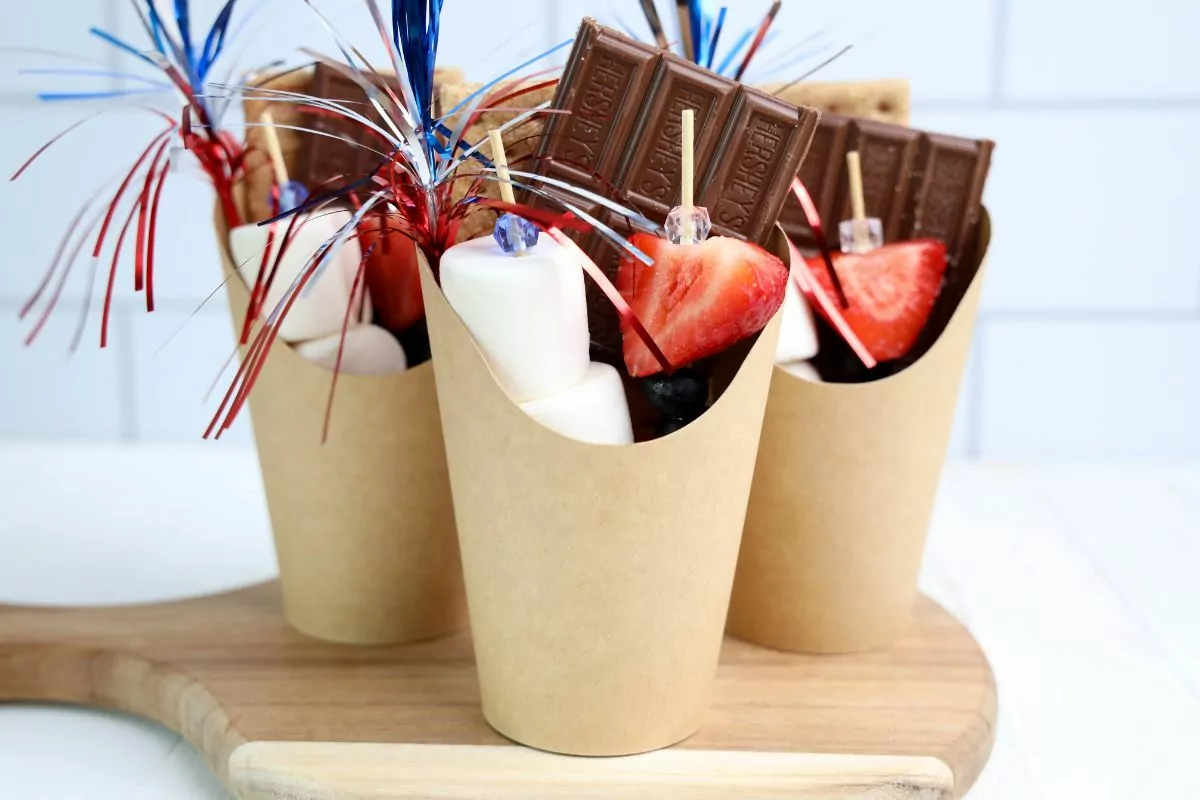 brown paper cups filled with ingredients to make smores