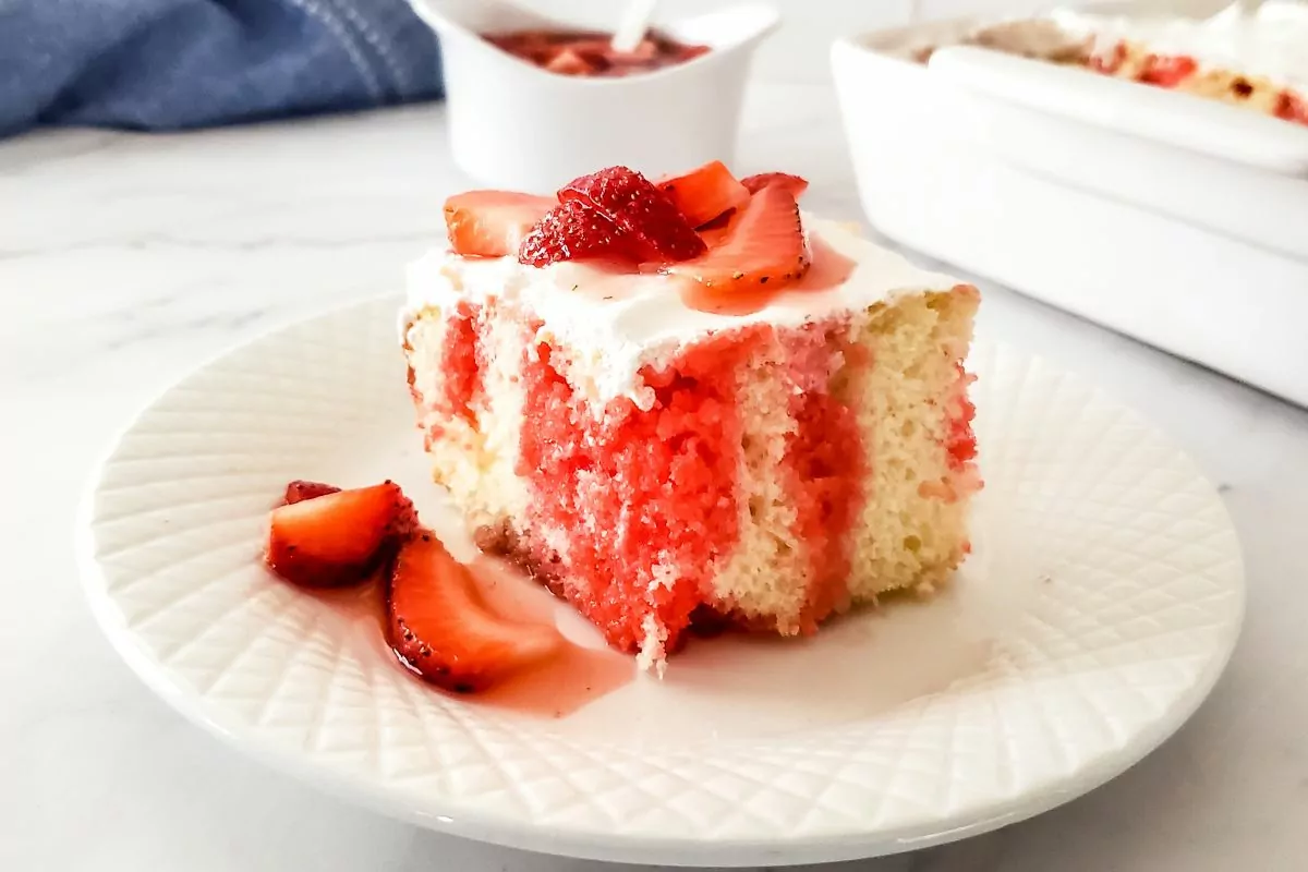 Slice of Strawberry Poke Cake on a white plate