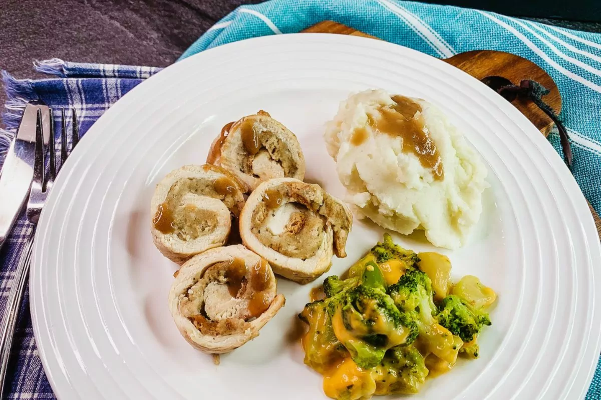 chicken roll ups with mashed potatoes, gravy and broccoli in cheese sauce.