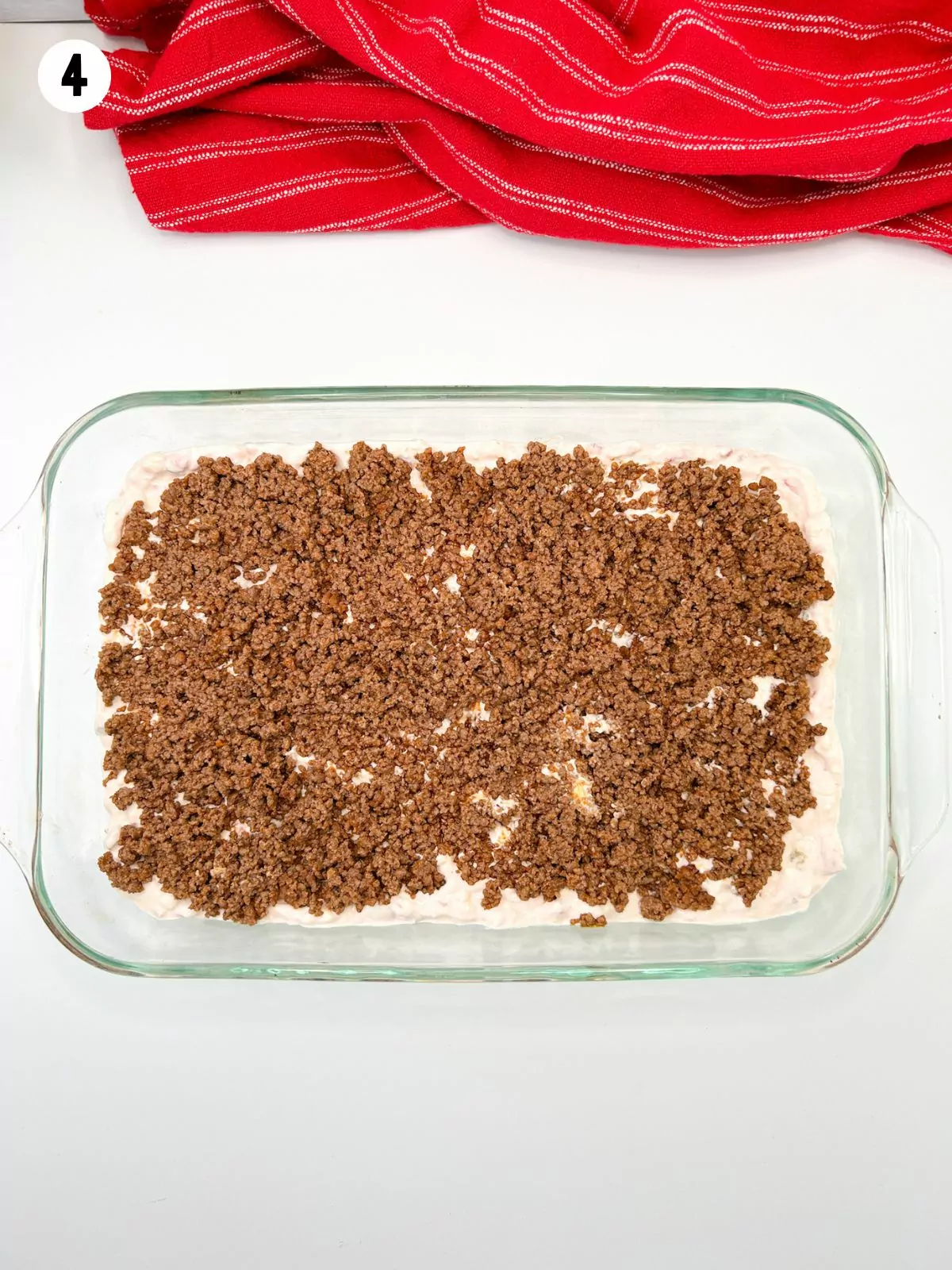 casserole dish with seasoned meat, cream cheese mixture.
