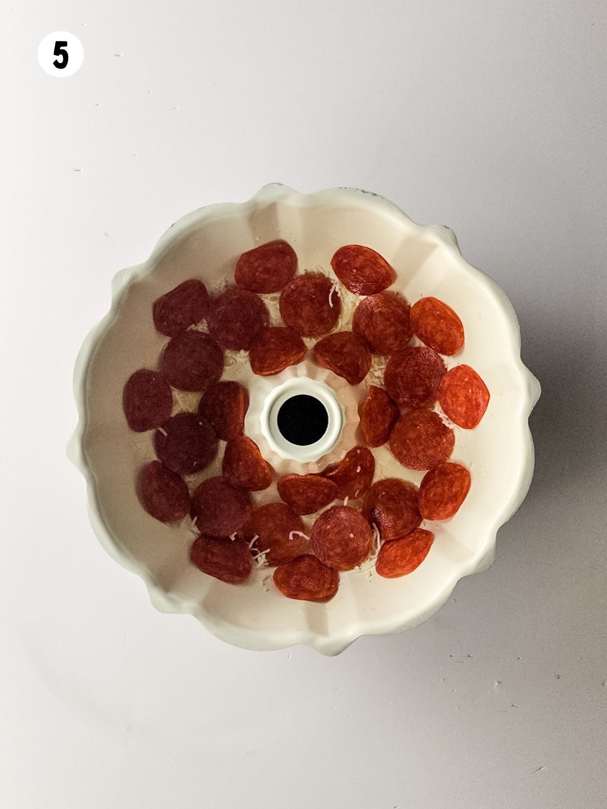 bundt pan with pepperoni slices in the bottom.