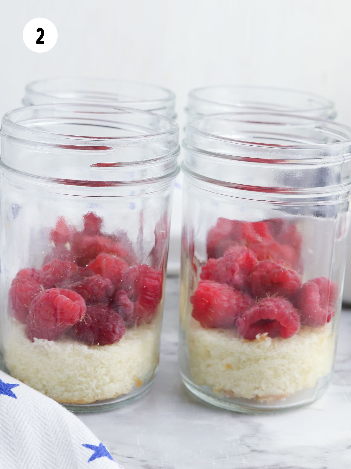 4 mason jars with pound cake and fresh raspberries.