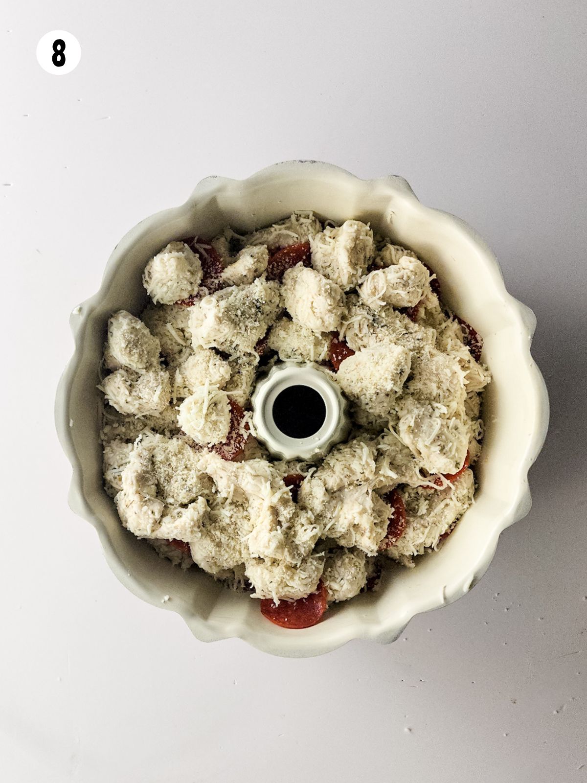 bundt cake pan with biscuits cut up, cheese and pepperoni slices.