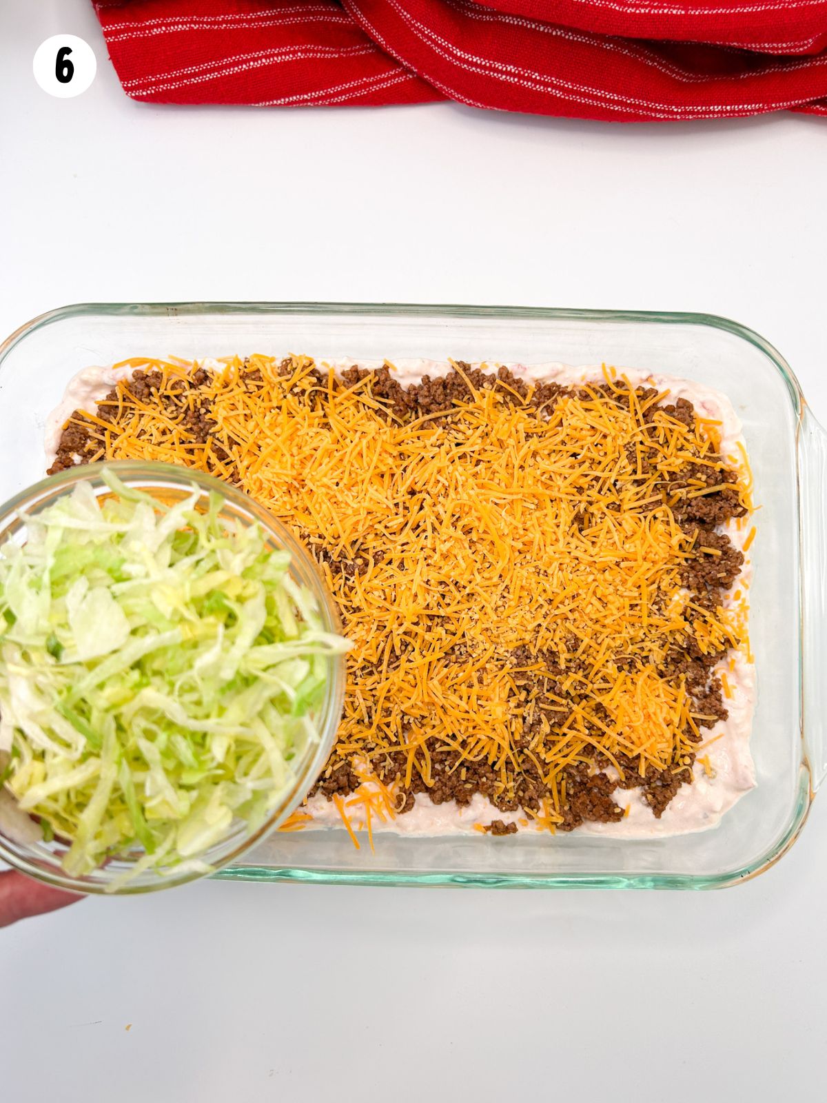 bowl of shredded lettuce over taco dip.