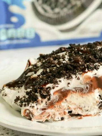 a slice of Oreo Pudding Dessert on white plate with package of cookies in background.