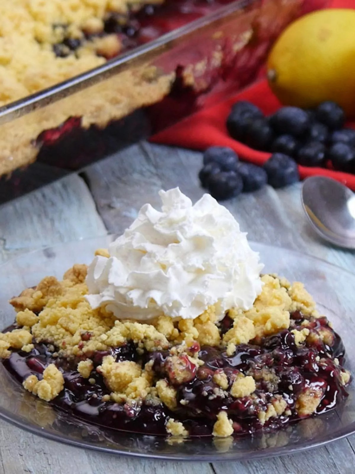 blueberry lemon dump cake on plate with whipped cream.