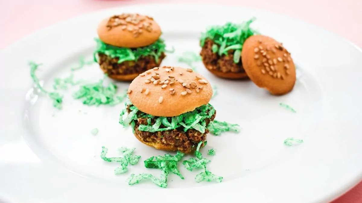 mini cookies that look like hamburgers, with sesame buns and shredded coconut lettuce.