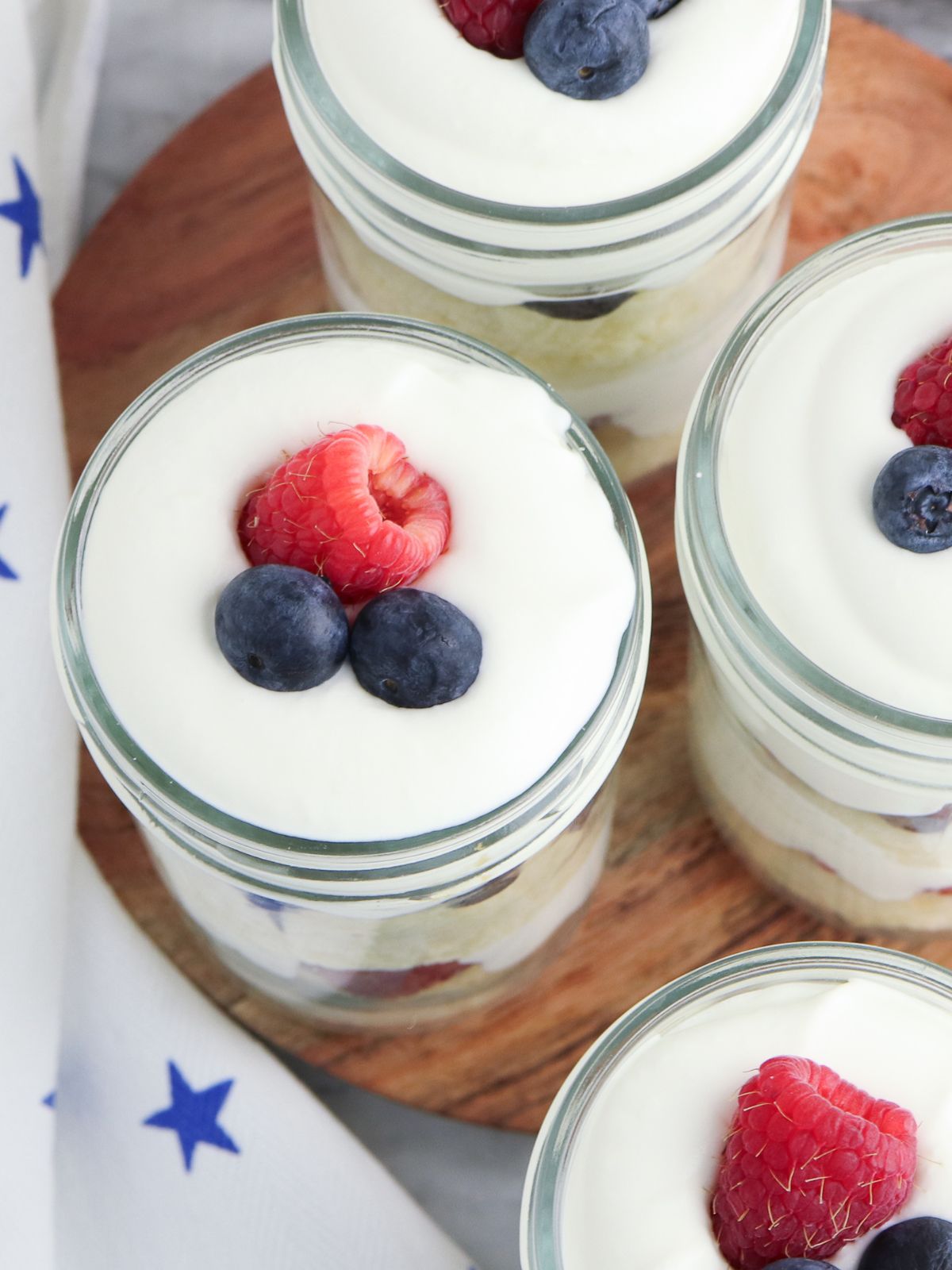 overhead view of mason jars filled with dessert, whipped cream and fruit.