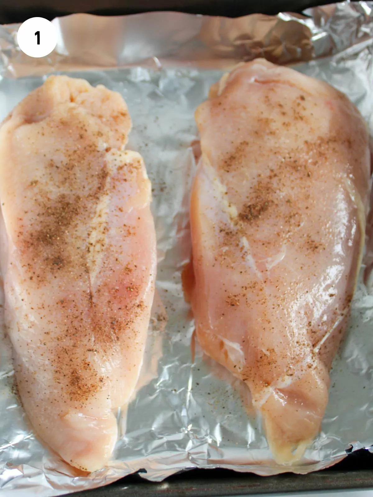 Chicken breasts on foil seasoned with salt and pepper