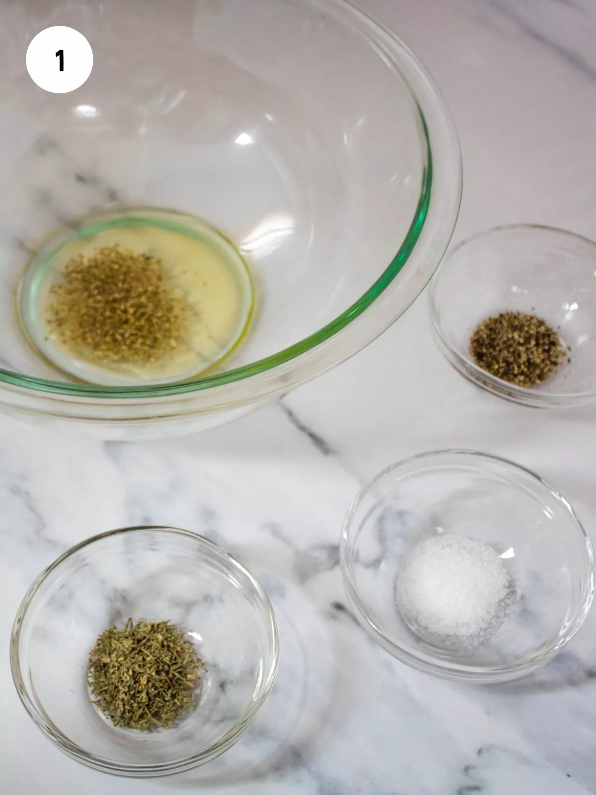 oil and seasonings being combined in a clear mixing bowl