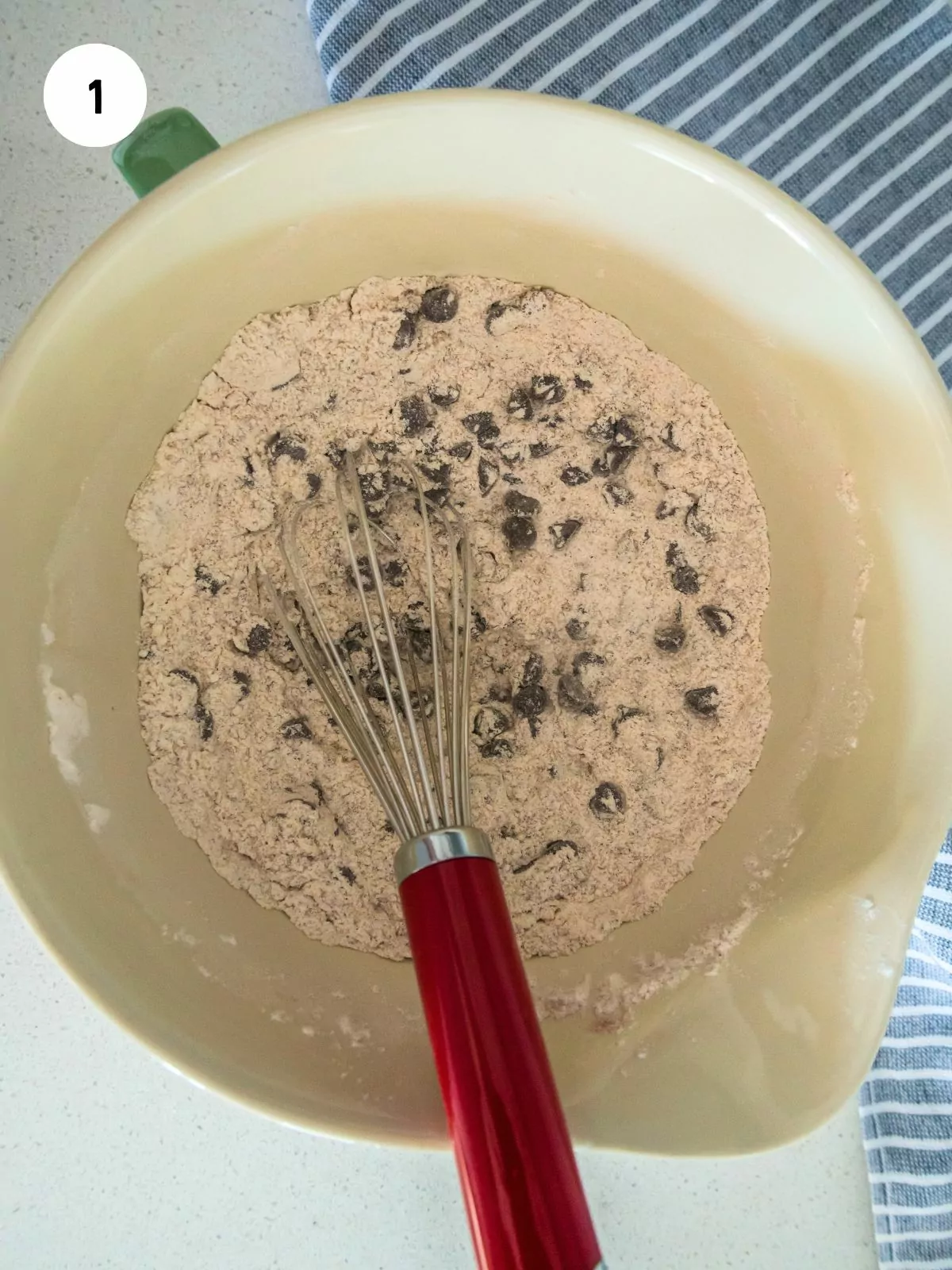 Flour mixture and chocolate chips in a mixing bowl with a whisk