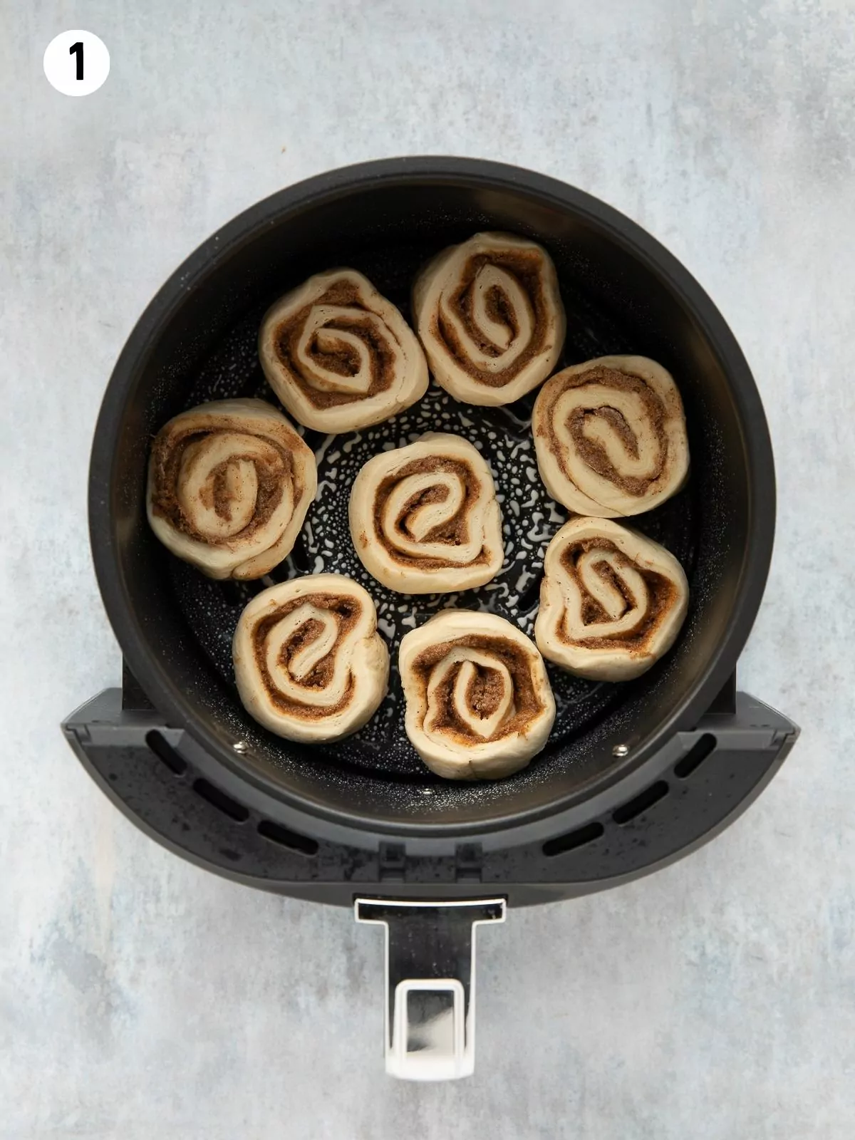 cinnamon rolls added to the basket of an air fryer