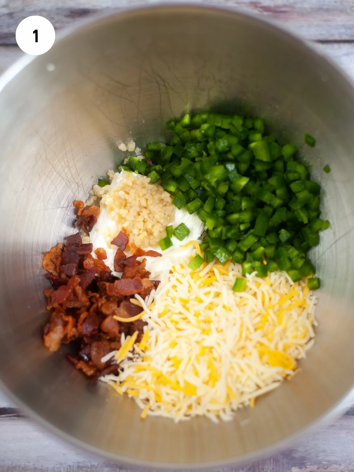 shredded cheese, cream cheese, jalapeños, and bacon, and garlic added to a metal mixing bowl