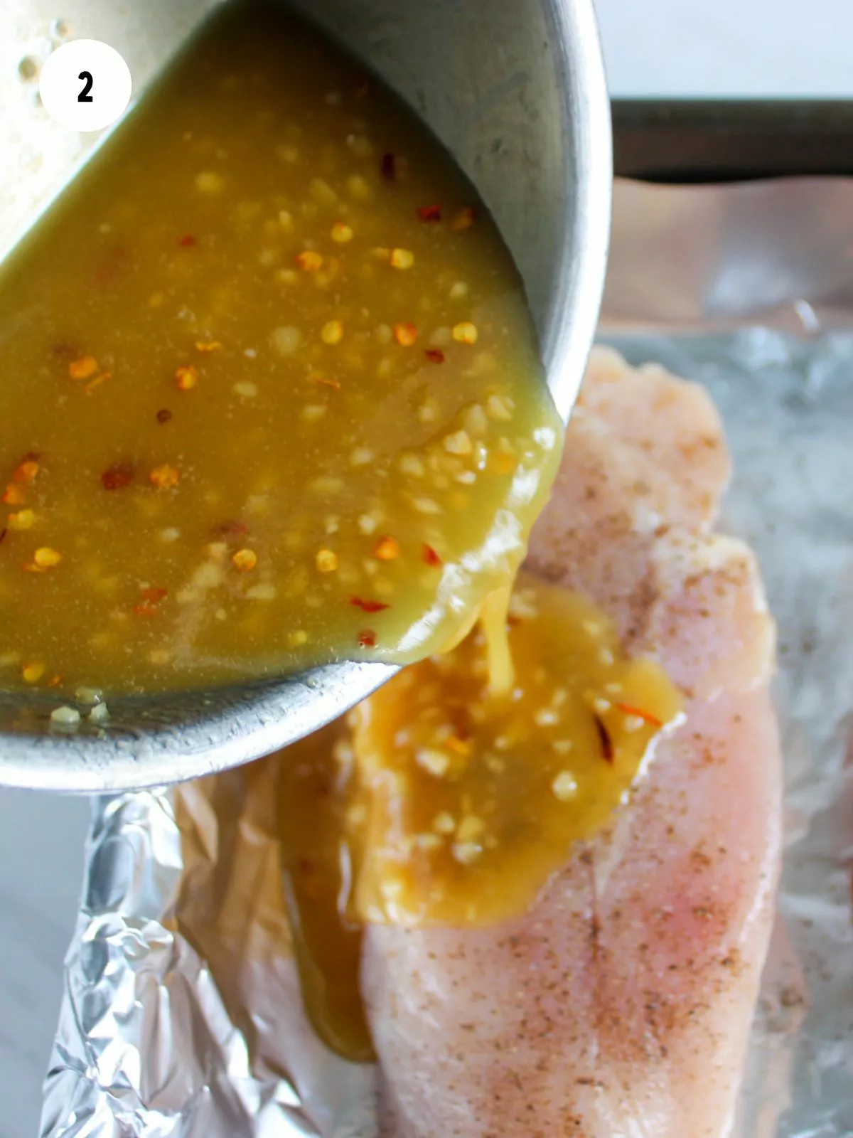 Honey garlic sauce being poured over a chicken breast