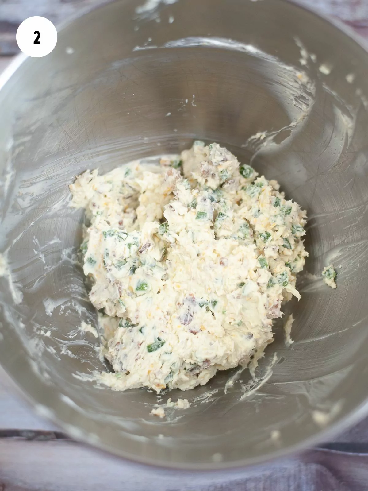 shredded cheese, cream cheese, jalapeños, and bacon, and garlic combined in a metal mixing bowl