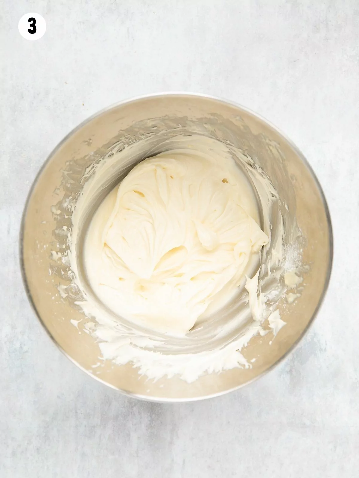 Cream cheese frosting in a stainless steel mixing bowl