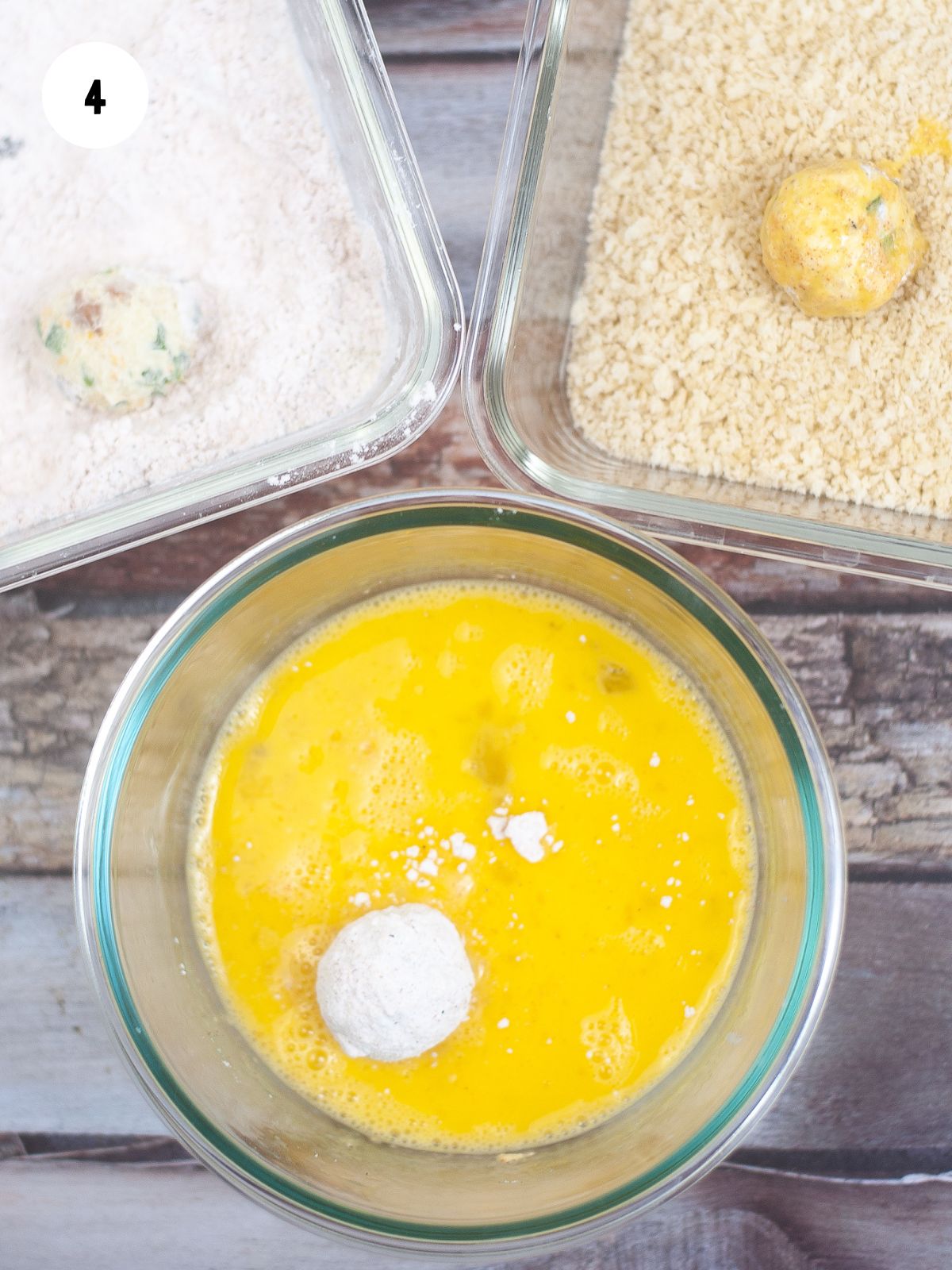 Breading station set up with a bowl of beaten eggs, pan of flour, and pan of panko