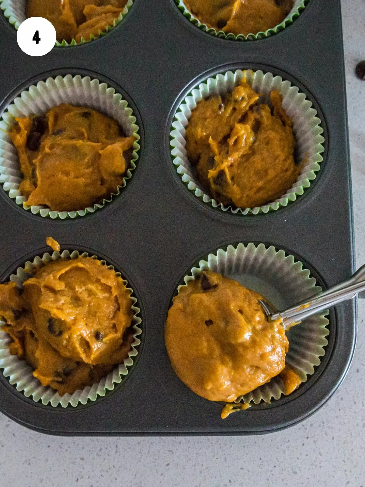 pumpkin muffin batter being scooped into muffin liners