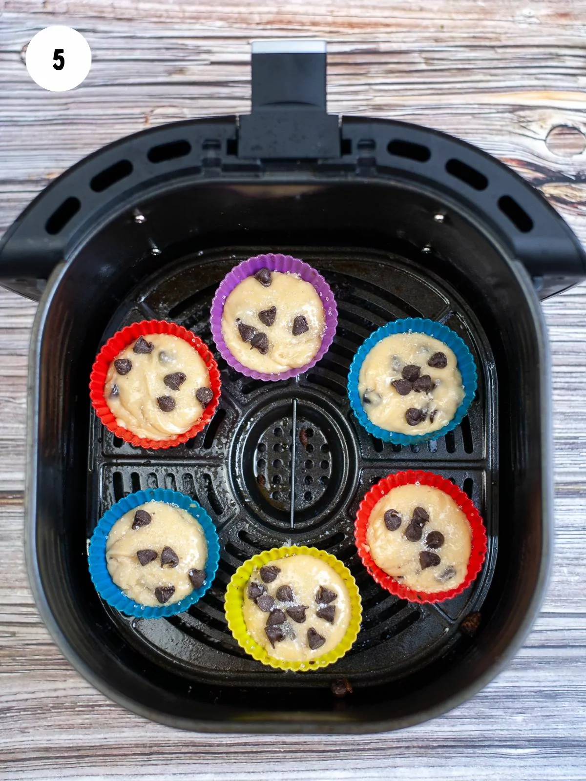 muffin batter added to silicone muffin molds in the basket of an air fryer