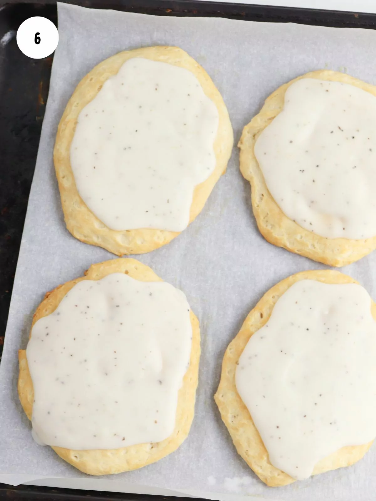 white gravy spread on baked biscuits