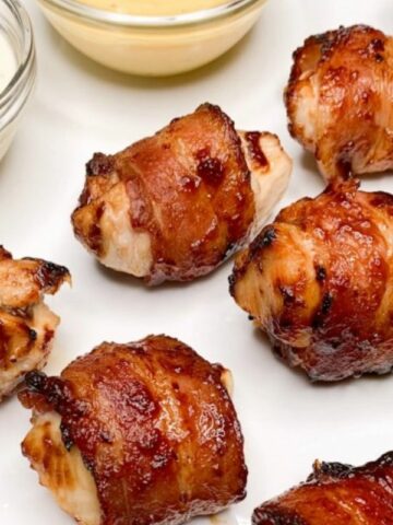 plate of chicken bites wrapped in bacon with bbq sauce.