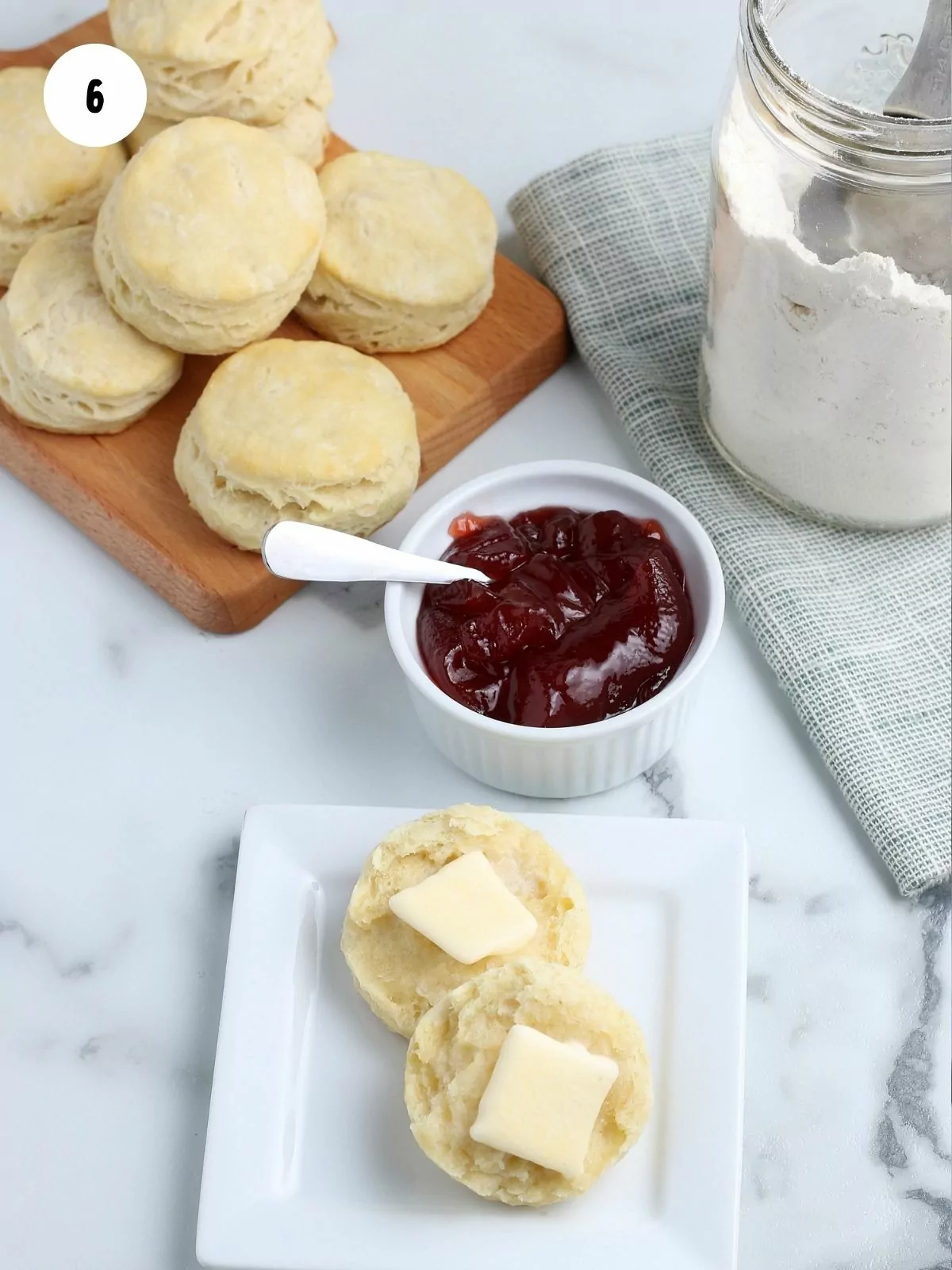 Baked biscuits with pats of butter and bowl of jam