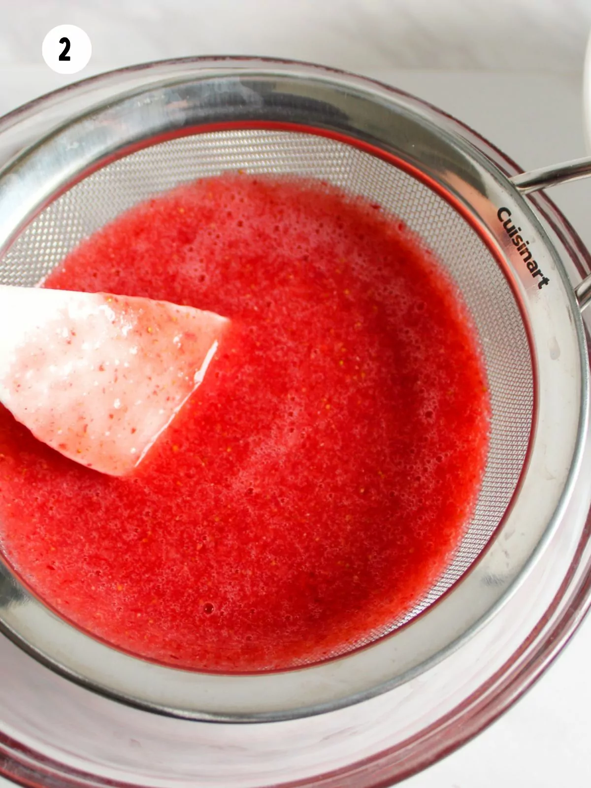 strawberry puree in a wire mesh sieve.