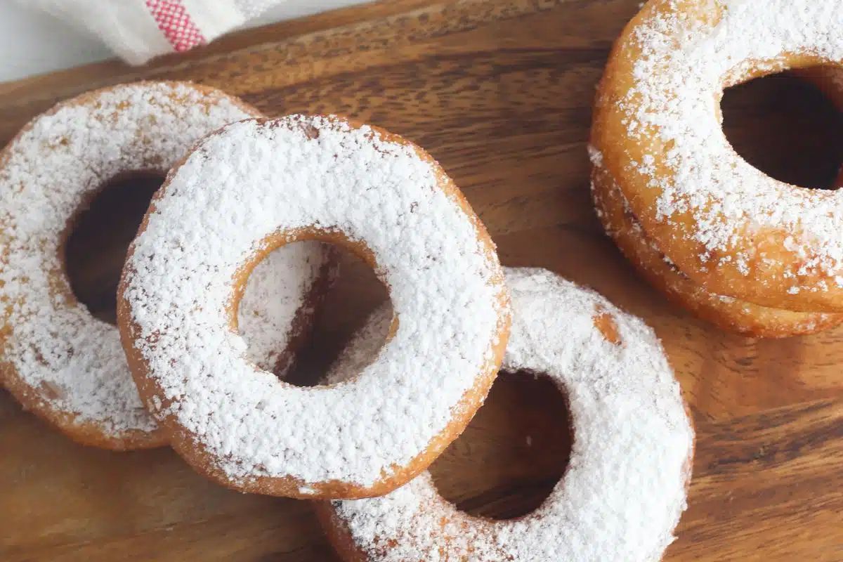 donuts with powdered sugar on cutting board.