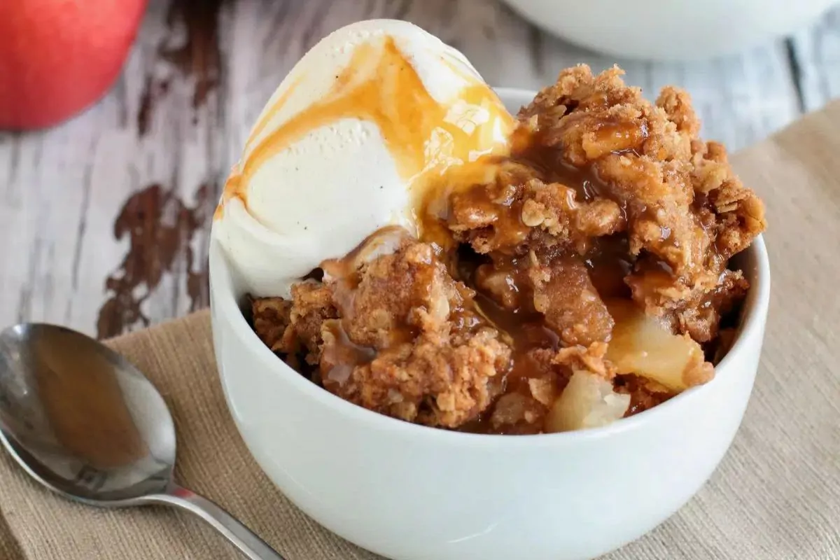 caramel apple cake in small white bowl with ice cream.