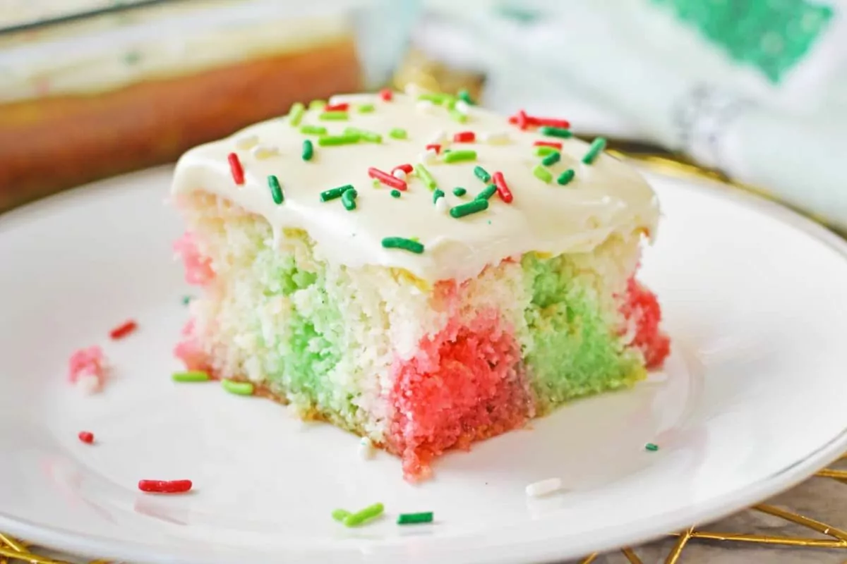 a white cake with red and green jello and fluffy white frosting.