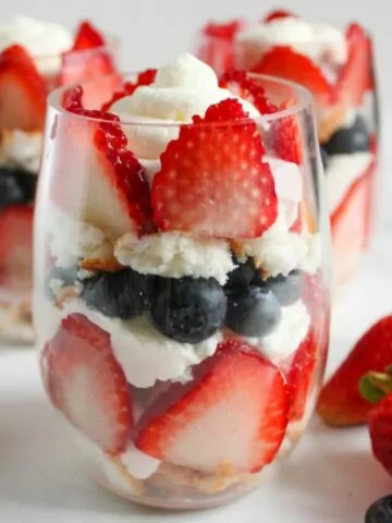 glass filled with strawberries, blueberries, whipped cream and angel food cake.