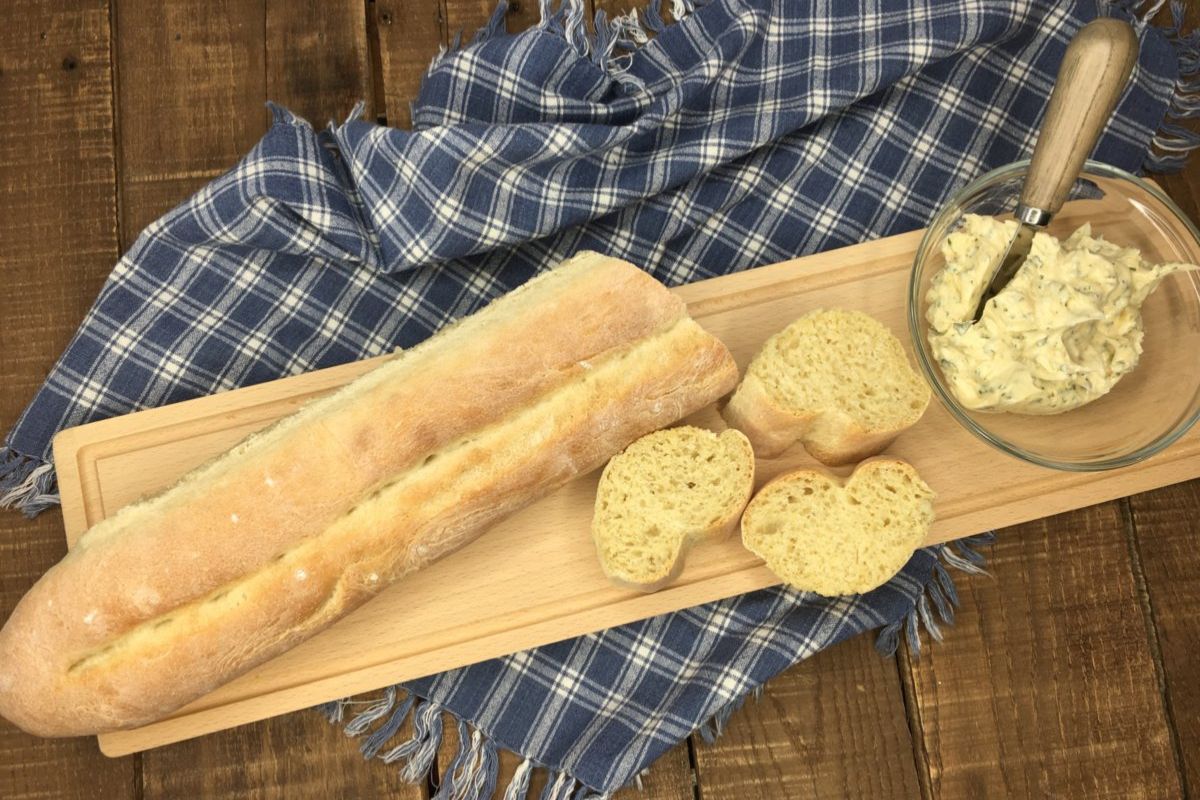 Homemade French Bread on cutting board with butter in bowl. MSN.