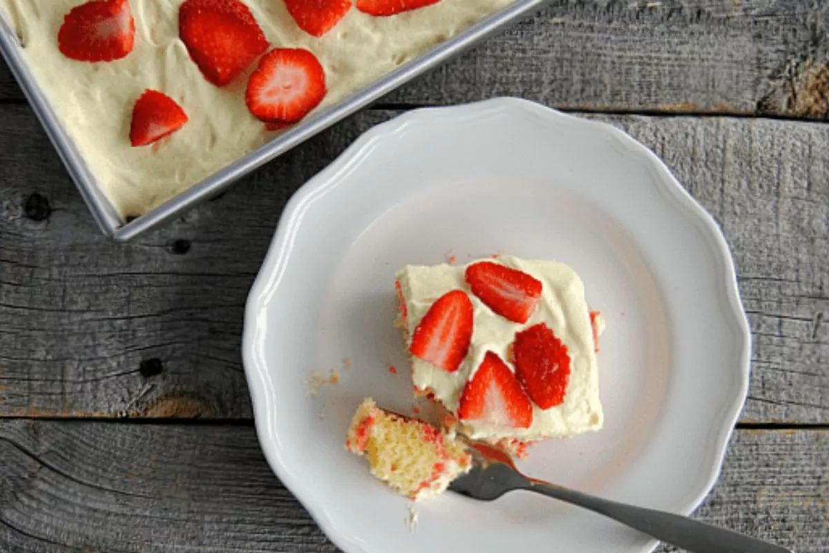 a slice of lemon cake on a plate with strawberry jello ribbons and fresh berry slices on top.