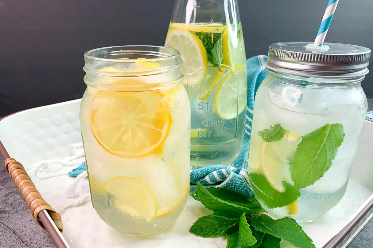 lemon mint water in mason jars on tray with sprigs of fresh mint.